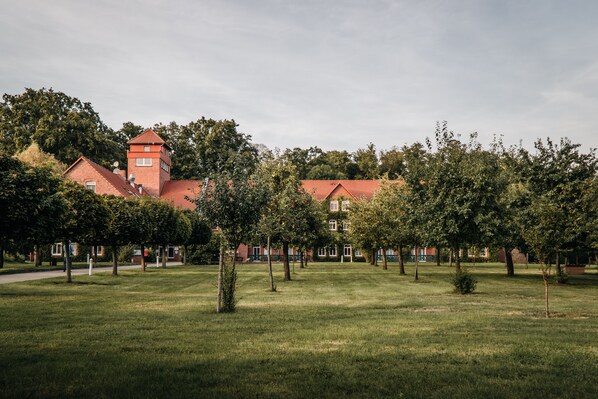 A large building with a tower, surrounded by a grassy area with trees. - Waldhotel Eiche (Lübbenau/Spreewald)