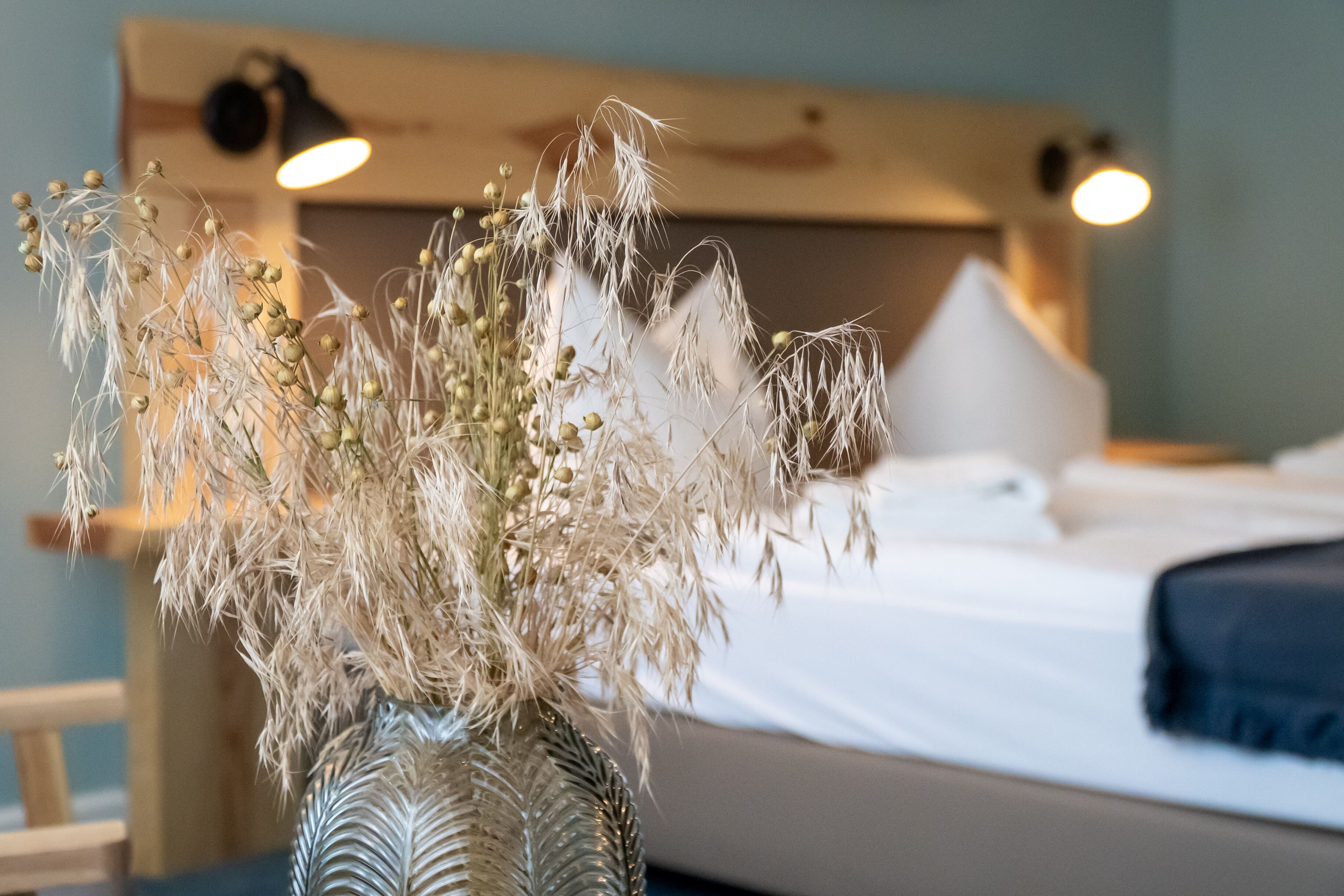 Una cama con sábanas blancas, cabecera de madera y dos lámparas de noche.