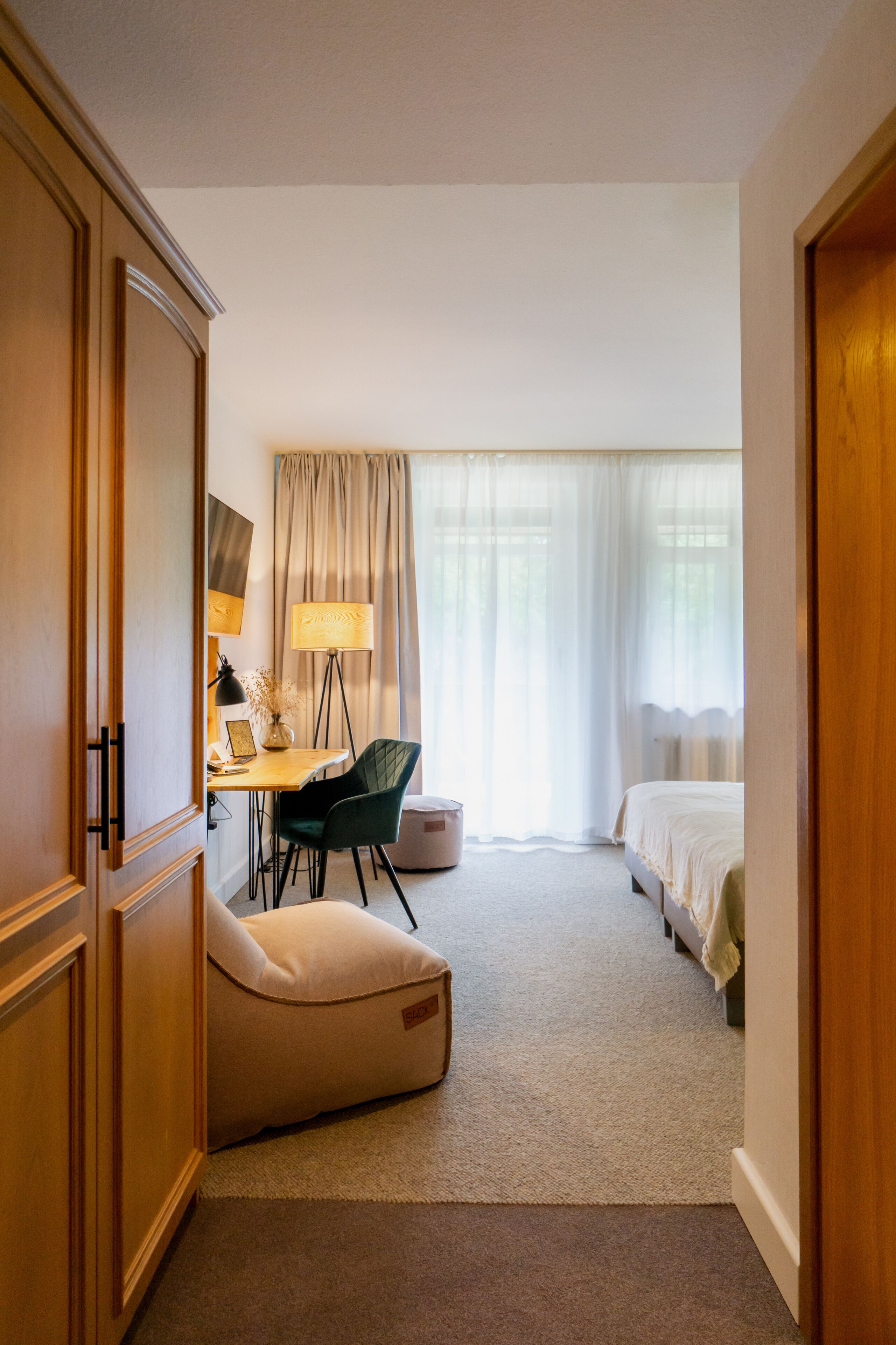 Una habitación de hotel con escritorio, silla, lámpara y cama.