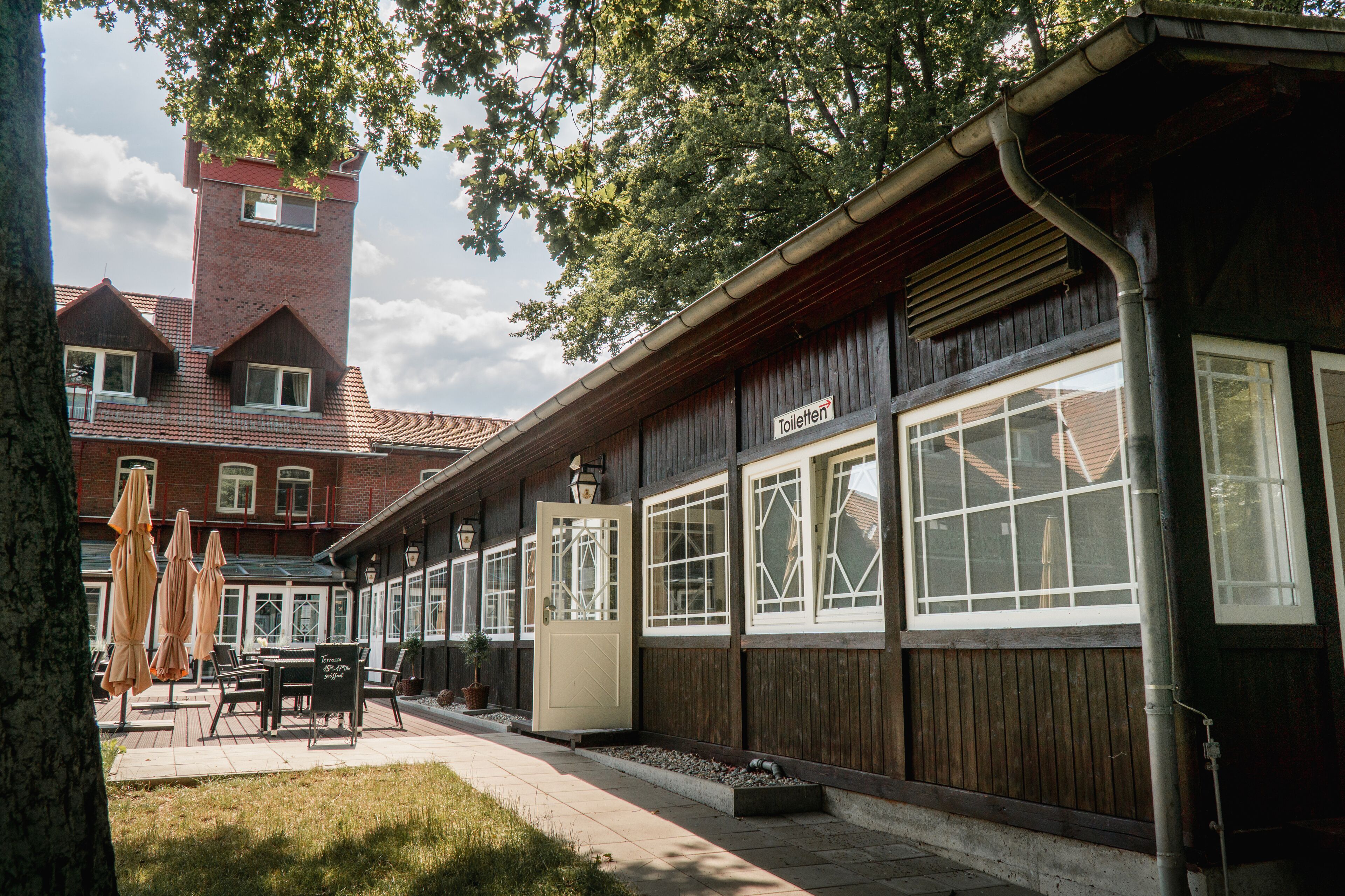 Ein Gebäude mit Holzfassade, großen Fenstern und einem Schild, das eine Toilette anzeigt.