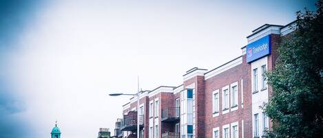 A Travelodge hotel with a blue sign, brick facade, and a dome structure in the background.