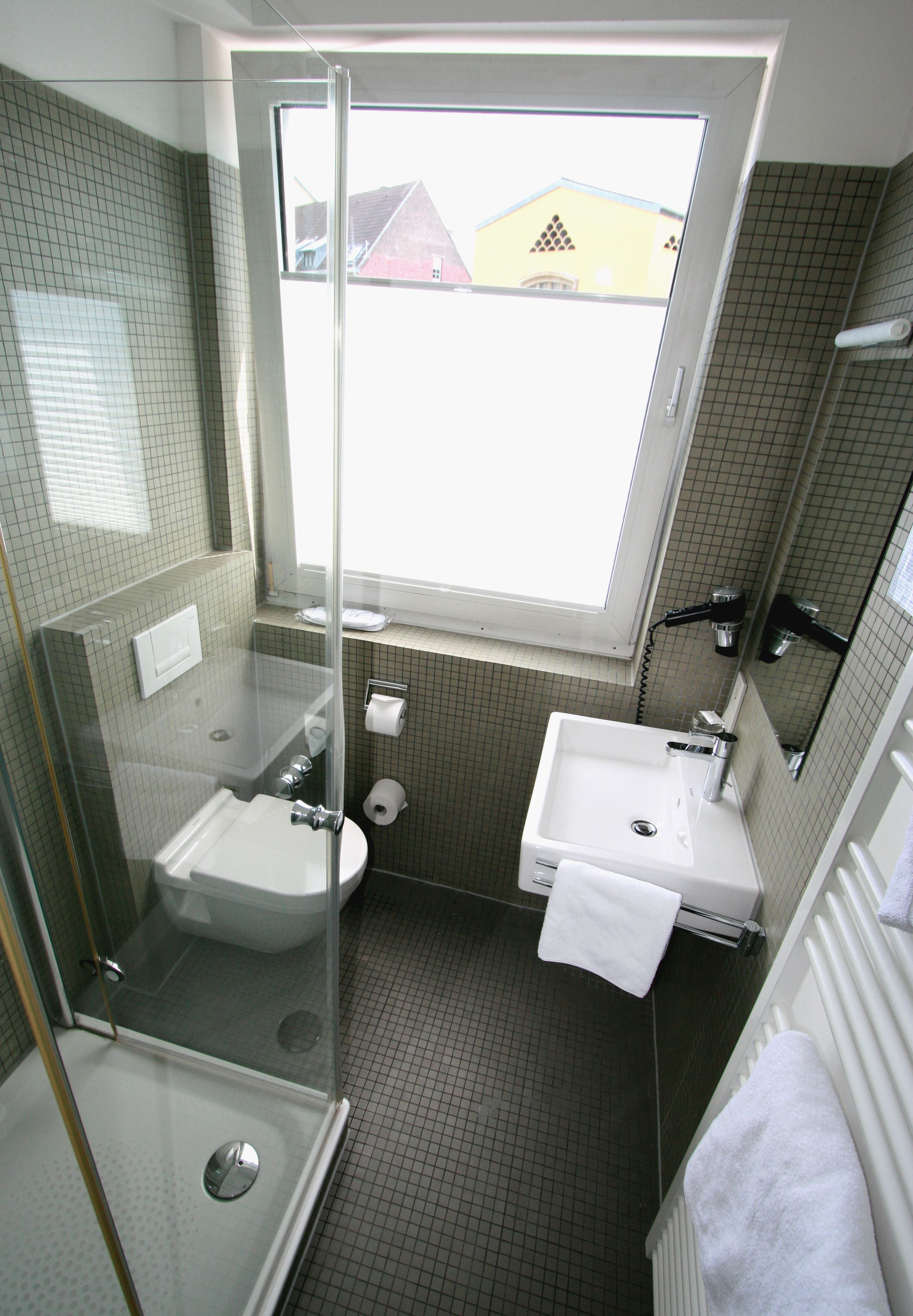 A compact bathroom with a shower, sink, and toilet.