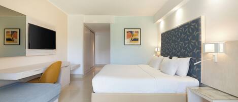 Een moderne hotelkamer met een groot bed, een bureau met stoel, een flatscreen televisie en een wandlamp.