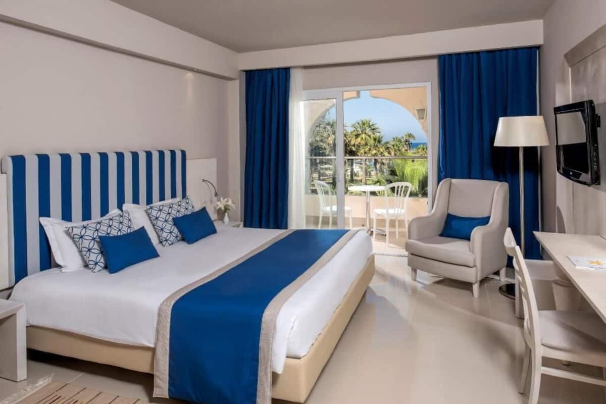 A hotel room with a bed, a desk, a chair, and a TV.