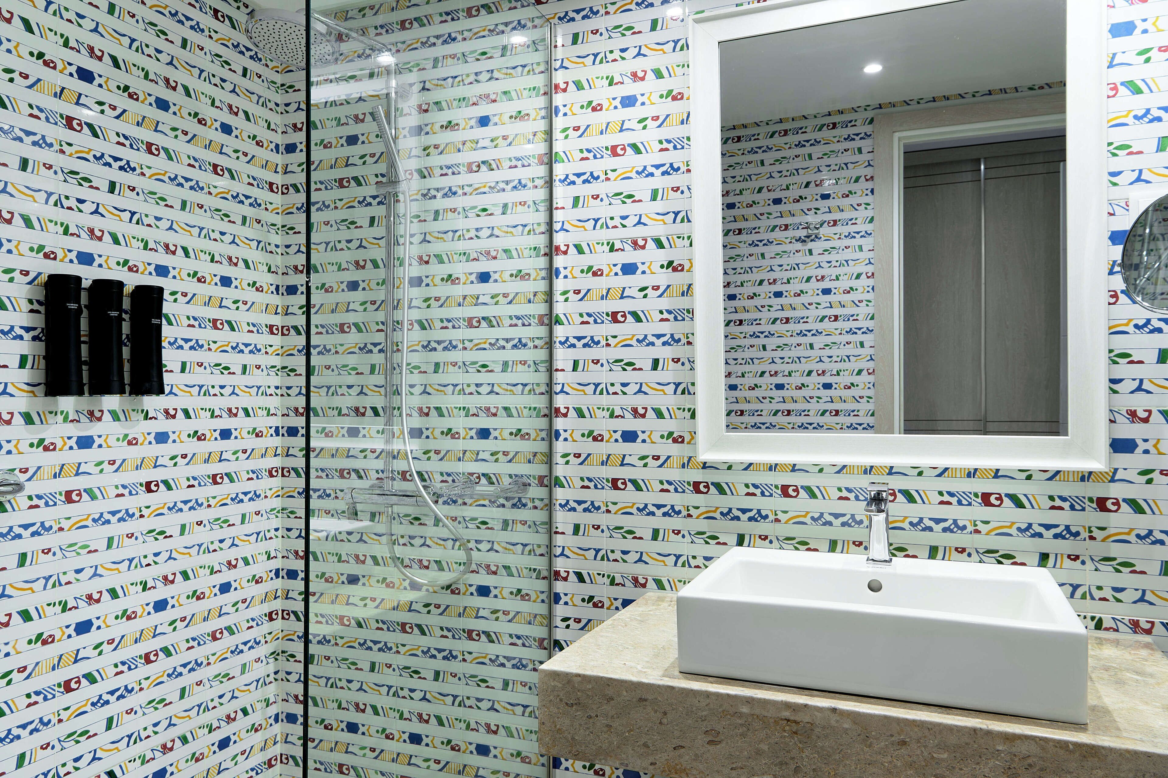 A bathroom with patterned tiles, a white sink, and a shower area.