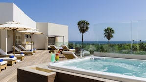 Un espace piscine aménagé sur le toit, avec des chaises longues, des parasols et un jacuzzi.