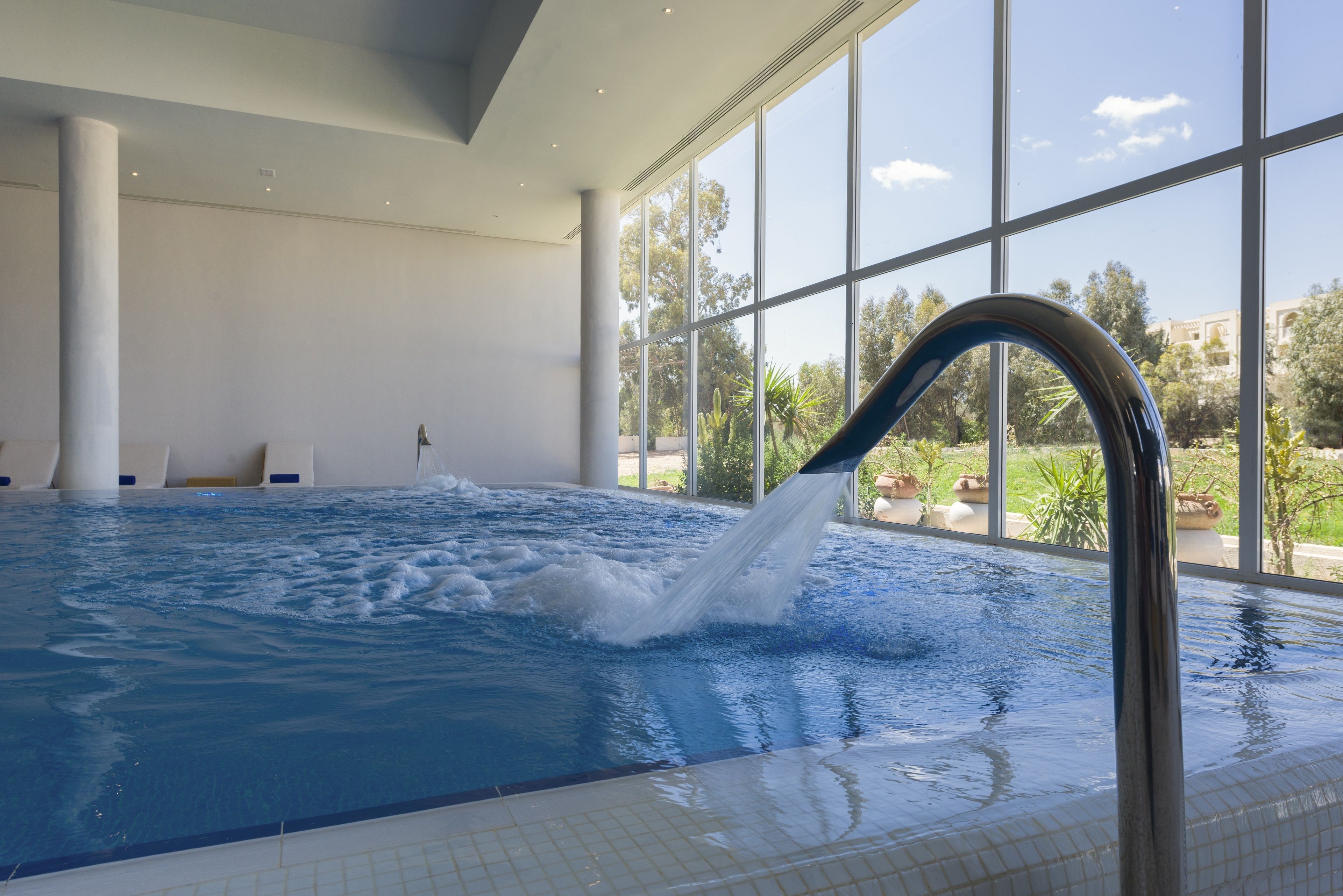 Una amplia piscina interior con vista despejada al exterior gracias a grandes ventanales.