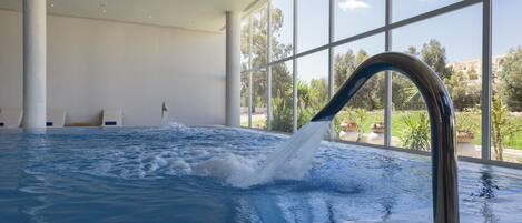 Una amplia piscina interior con vista despejada al exterior gracias a grandes ventanales.