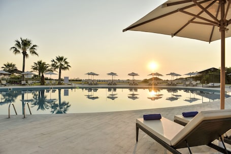 Una piscina techada, una piscina al aire libre, sombrillas