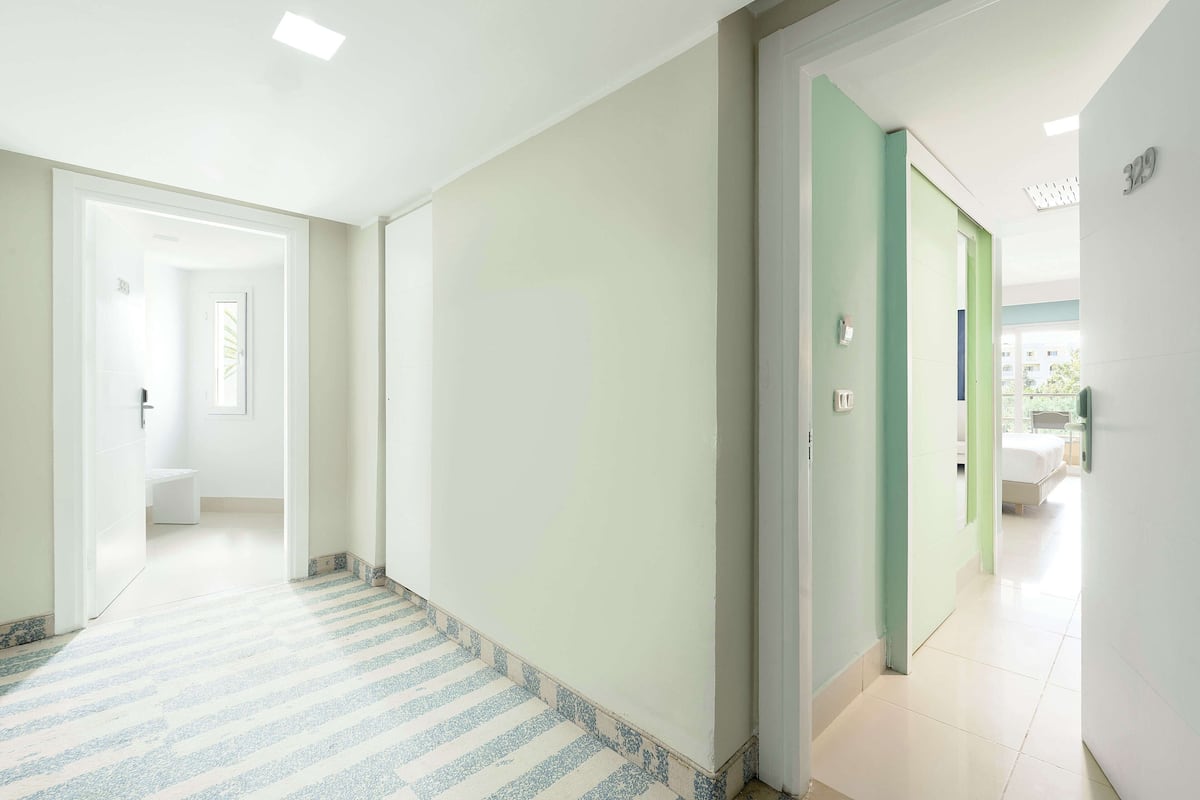 A hallway with a striped carpet leading to a bathroom and a bedroom.