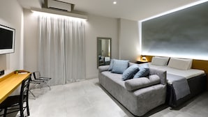 Una habitación de hotel moderna con sofá, cama, escritorio y un espejo grande.