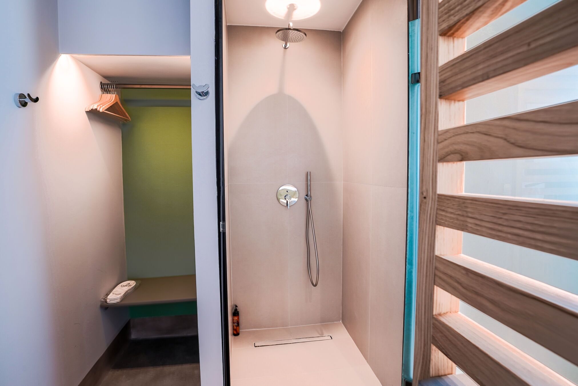 A modern bathroom with a shower, a towel rack, and a small seating area.
