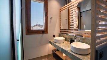 A modern bathroom with two sinks, a large mirror, and a window.