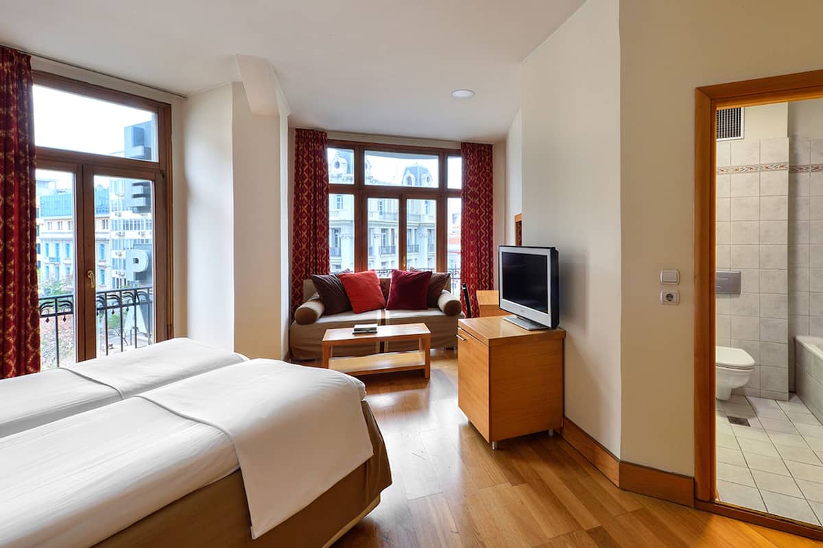 Ein Hotelzimmer mit Bett, Sofa, Fernseher und Badezimmer.