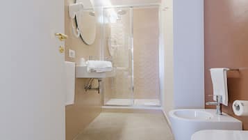 A modern bathroom with a glass shower enclosure, a sink, and a toilet.