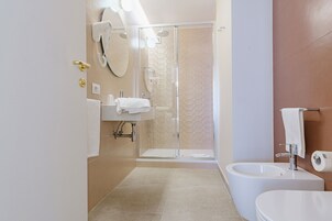 A modern bathroom with a glass shower enclosure, a sink, and a toilet.