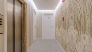 A hallway with a door labeled 805, a wall with a floral pattern, and a fire alarm on the right. - Boston Hotel (Bari)