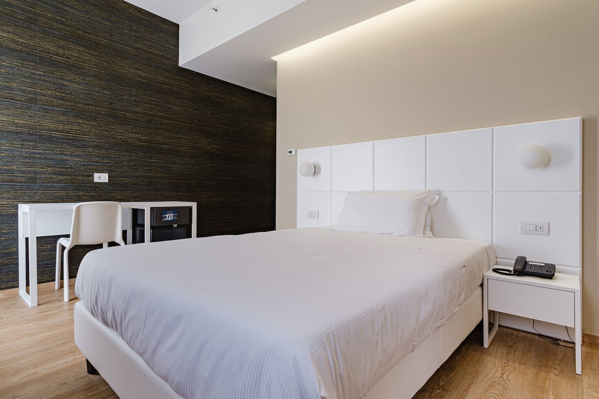 Une chambre d’hôtel moderne, dotée d’un grand lit, d’un bureau et d’une chaise.