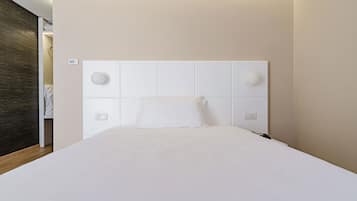 Ein modernes Hotelzimmer mit einem großen Bett, einem weißen Kopfteil und Holzboden.