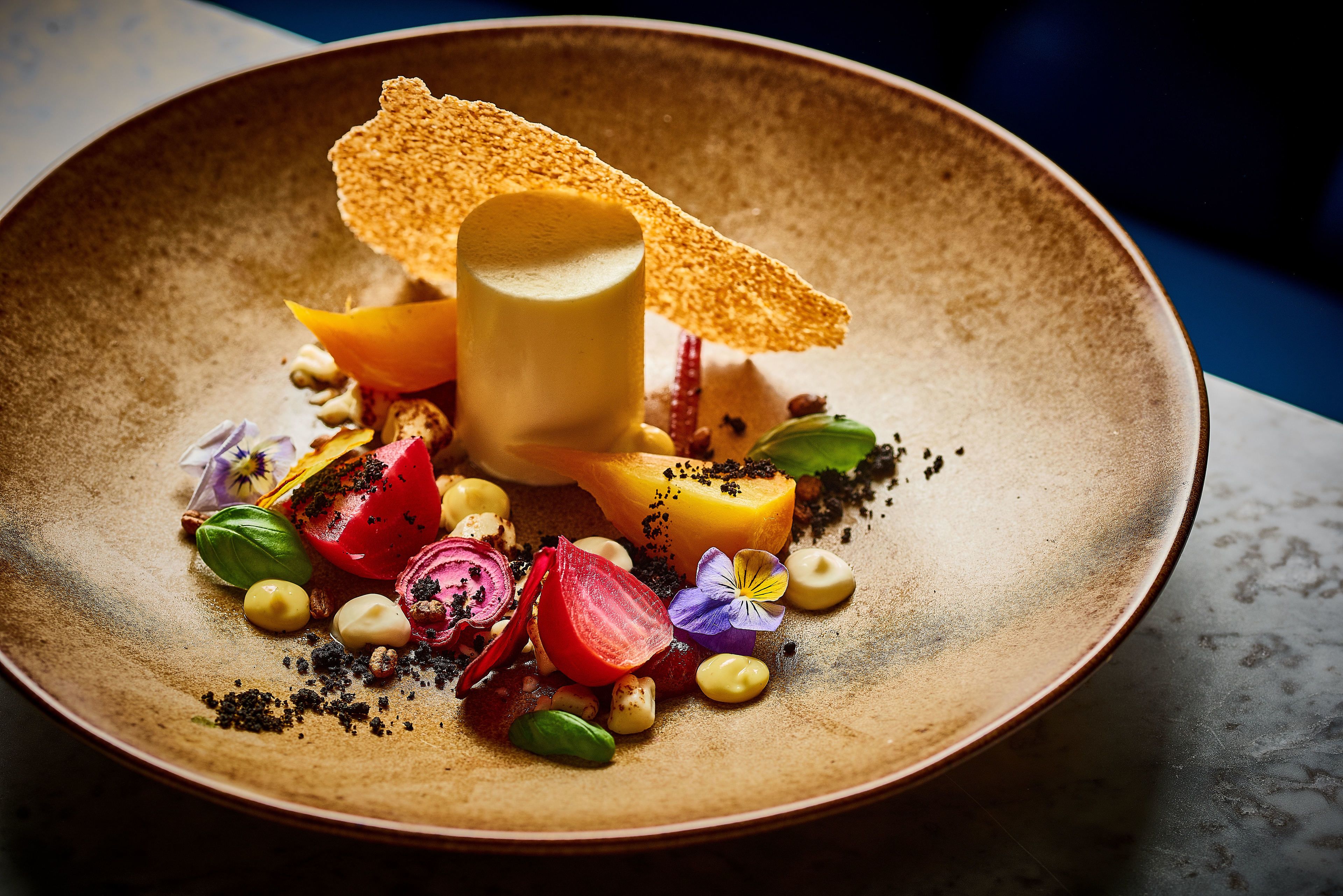 A plate with various food items including a cylindrical piece of food, vegetables, and garnishes.