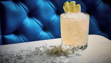 A glass of a light-colored beverage with ice cubes and a garnish on a marble surface.
