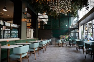 A restaurant with green cushioned booths, wooden tables, and hanging floral decorations.