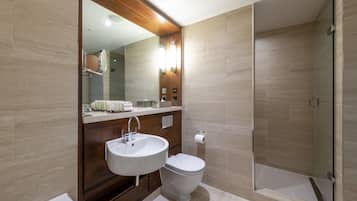 A modern bathroom with a double sink, toilet, and a glass-enclosed shower area.