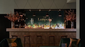 A bar area with a marble countertop, multiple stools, and a green sofa. - Apex City of London Hotel (London)