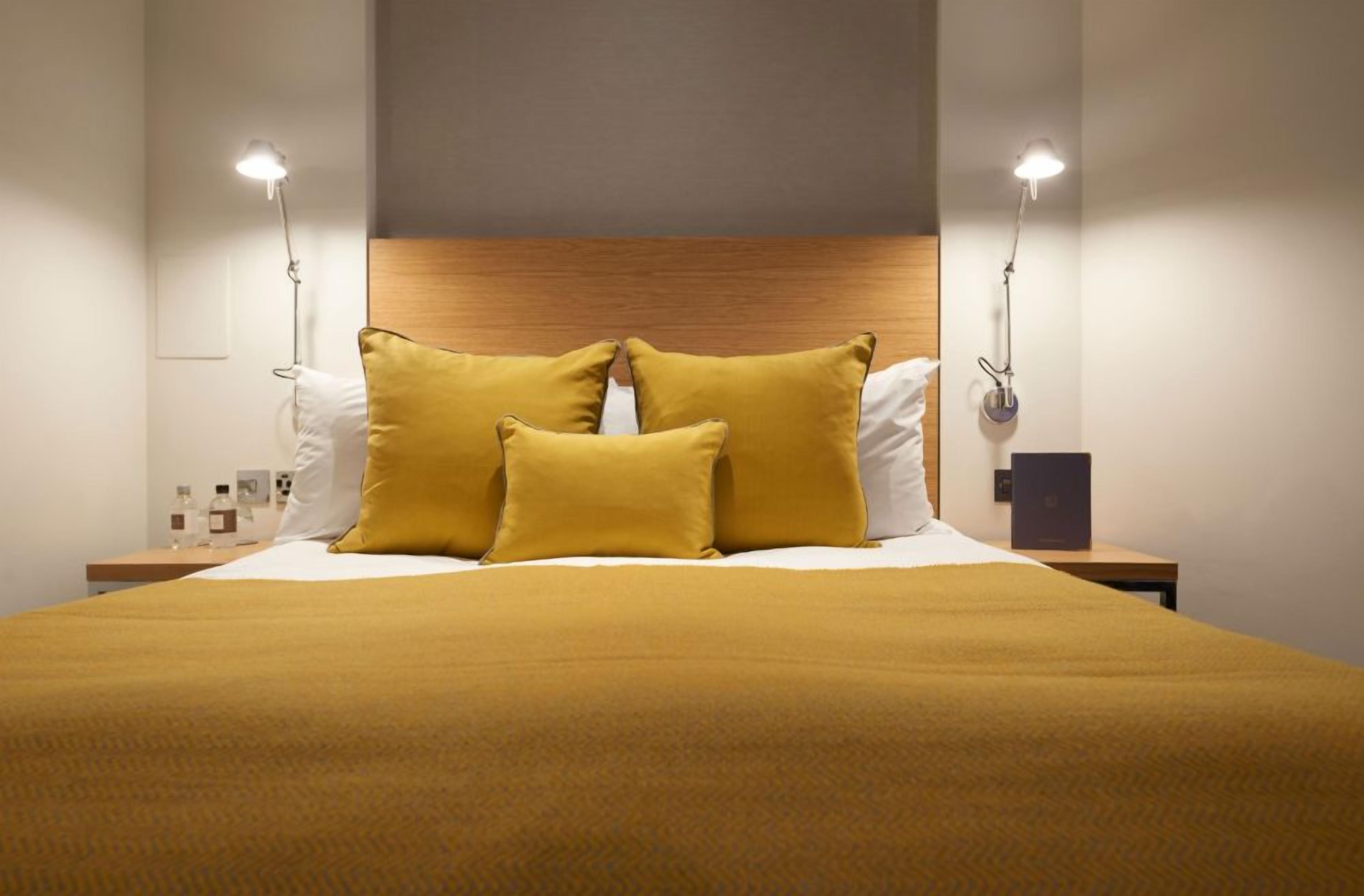 Habitación de hotel con una cama grande, dos lámparas de noche y un cabecero de madera.