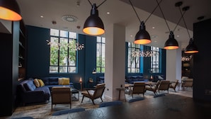 A modern lounge area with dark blue walls, comfortable seating, and pendant lighting. - Apex City of London Hotel (London)