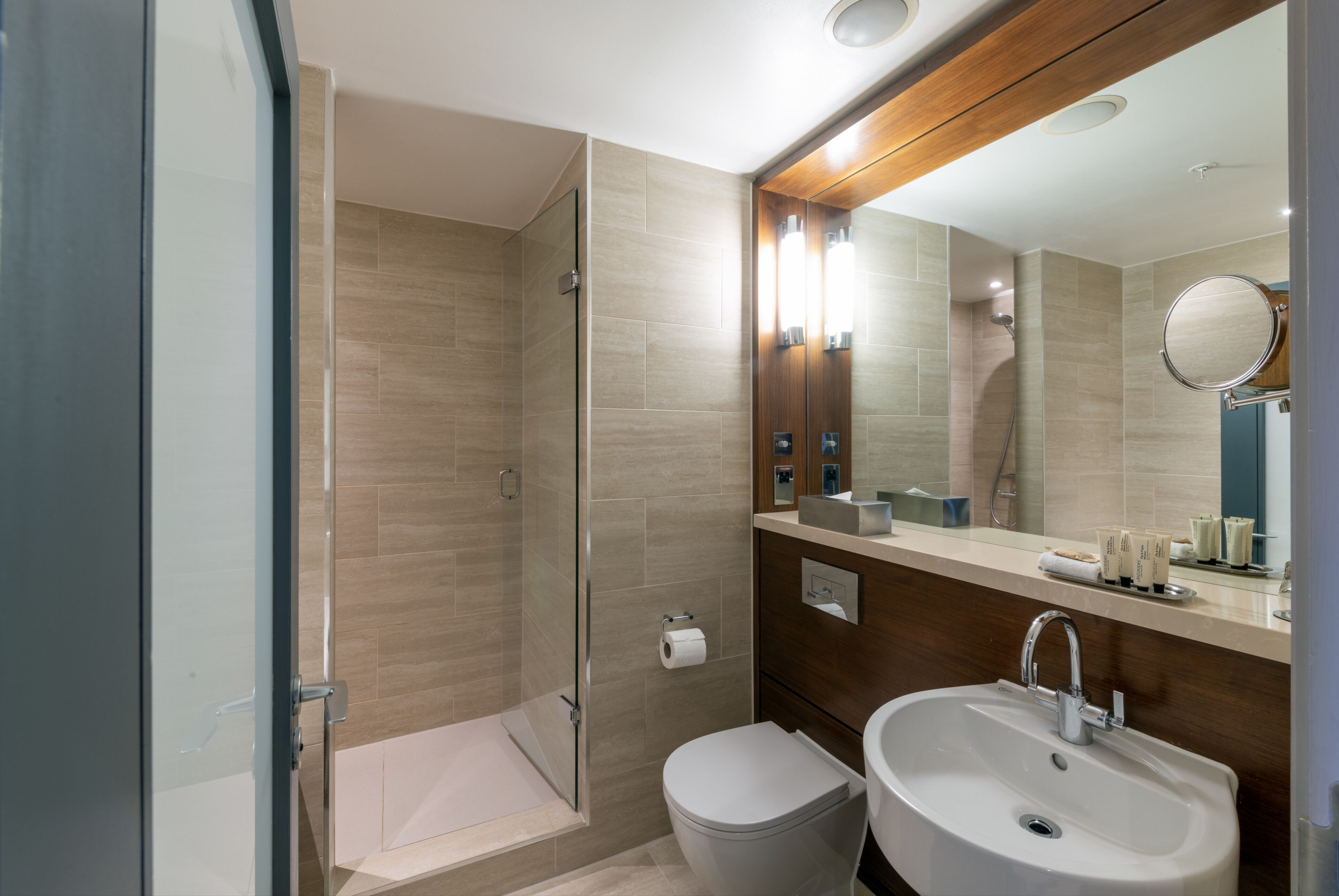 Un baño moderno con cabina de ducha de vidrio, inodoro y lavabo con espejo.