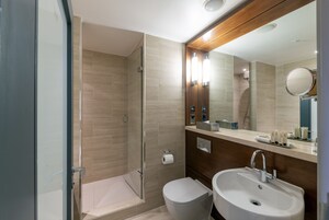 Un baño moderno con cabina de ducha de vidrio, inodoro y lavabo con espejo.