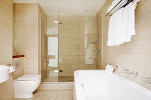 A modern bathroom with a glass-enclosed shower, a white toilet, and a large bathtub.