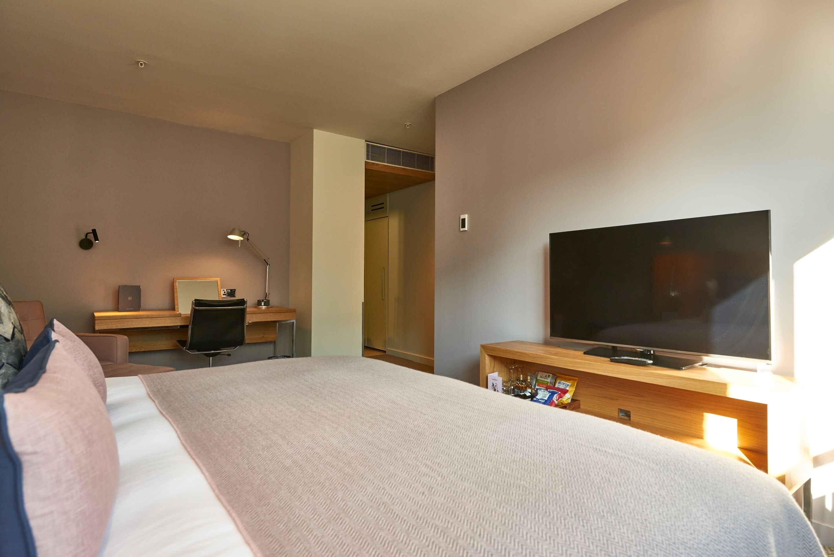 Een hotelkamer met een groot bed, een bureau met een computer, een televisie en een kledingkast.