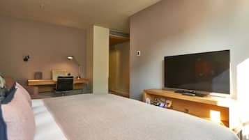 Een hotelkamer met een groot bed, een bureau met een computer, een televisie en een kledingkast.