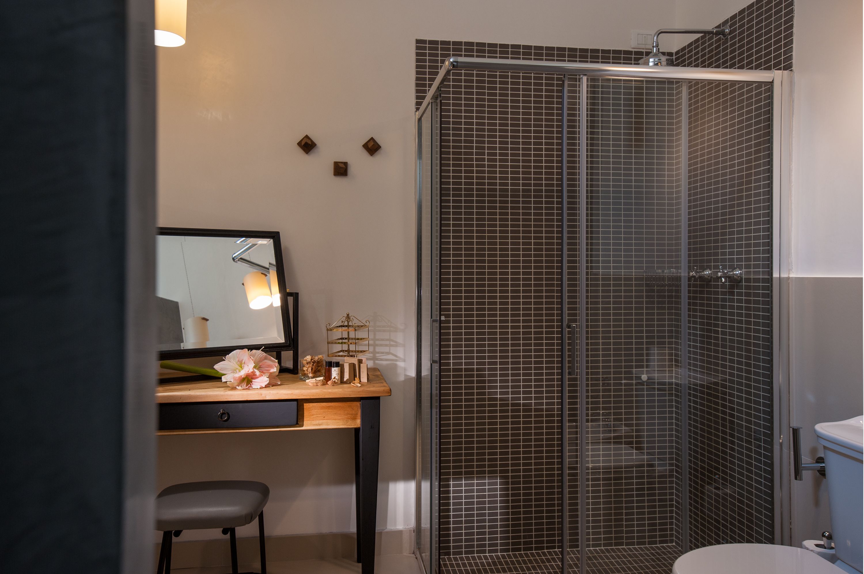 A modern bathroom with a glass shower enclosure, a wooden vanity with a mirror, and a toilet.