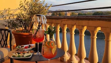 Un balcon avec une table dressée pour un repas, comprenant des assiettes de nourriture, une boisson et une plante en pot.