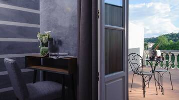 Une chambre moderne avec un mur à rayures grises, un bureau en bois, une chaise grise et un balcon avec une table et des chaises.