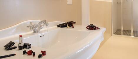 A bathroom with a large white bathtub, a mirror, and a shower area.