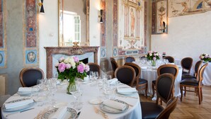 A formal dining room with a long table set for a meal, surrounded by chairs.