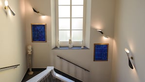 A staircase with a handrail, a window with frosted glass, and wall-mounted art and sculptures.