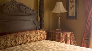 A bed with a patterned bedspread, a wooden headboard, a bedside table with a lamp, and a framed picture on the wall.