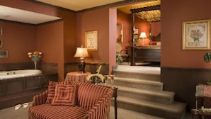 Ein Hotelzimmer mit einer gestreiften Couch, einem kleinen Tisch mit Lampe, einer Treppe und einem Badezimmer mit Badewanne.