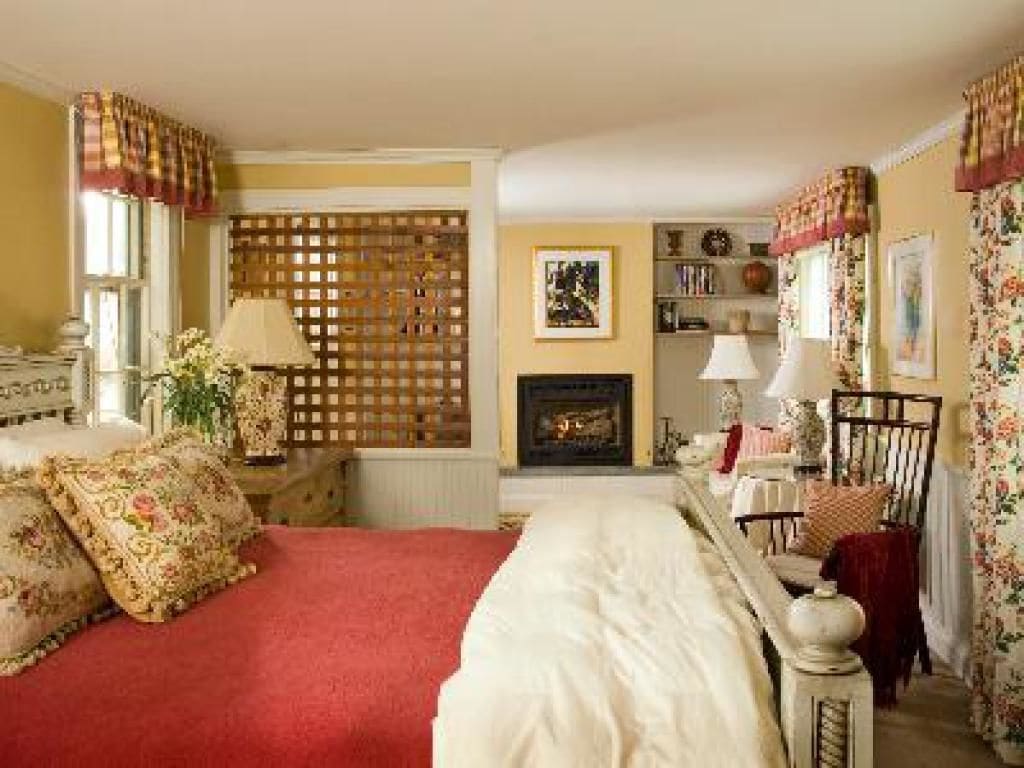 A traditional bedroom with a bed, a fireplace, and a bookshelf.