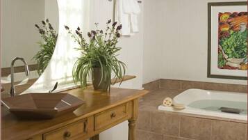 Ein Badezimmer mit einem Holzbadezimmerhocker, einem Waschbecken, einer Badewanne und einem großen Spiegel.