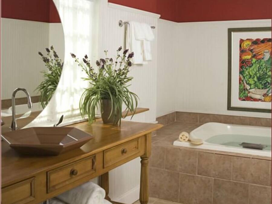 Ein Badezimmer mit einem Holzbadezimmerhocker, einem Waschbecken, einer Badewanne und einem großen Spiegel.