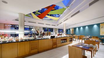 A modern breakfast area with a long counter, wooden cabinets, and a colorful ceiling design.