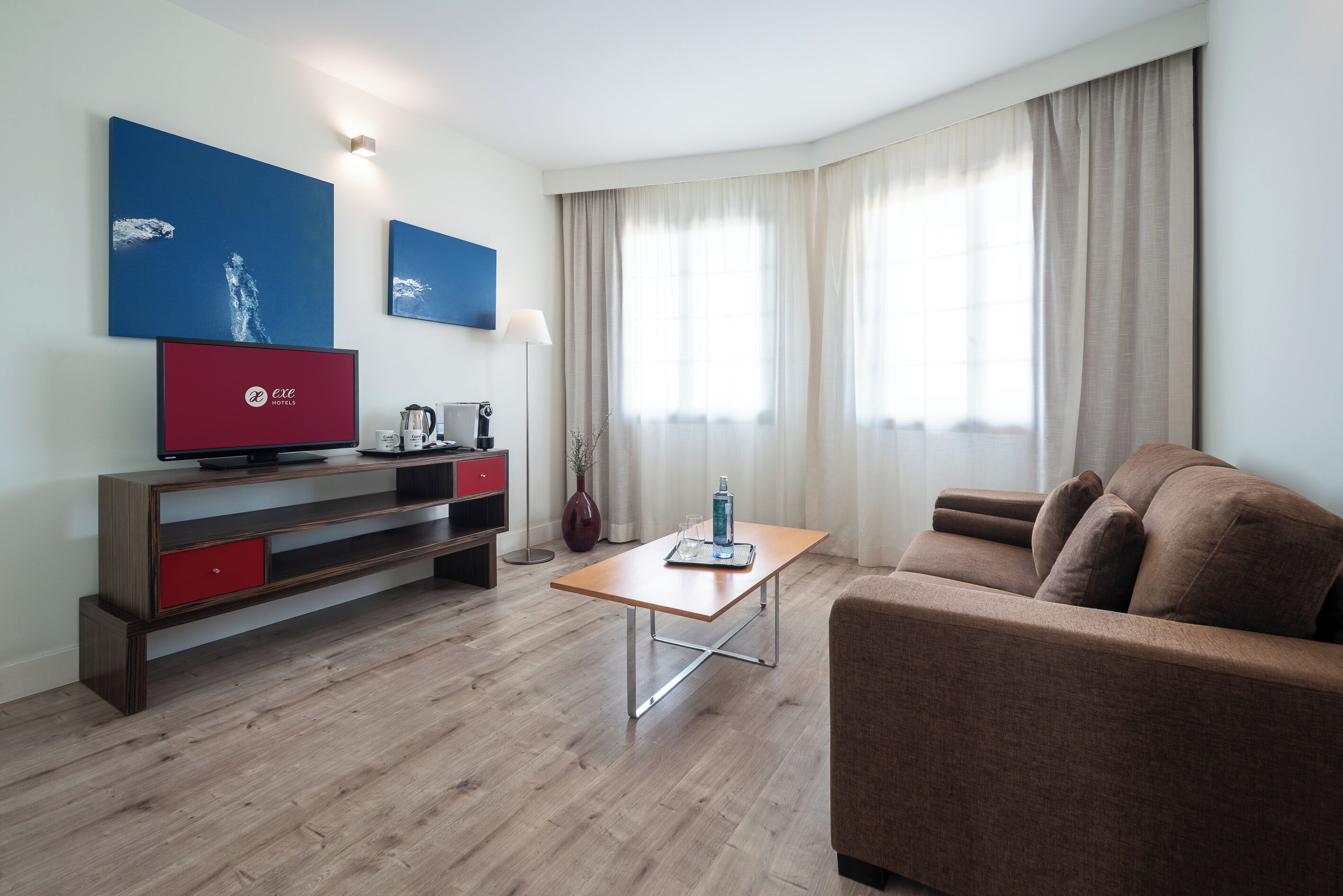 A modern living room with a sofa, a coffee table, a TV, and artwork on the wall.