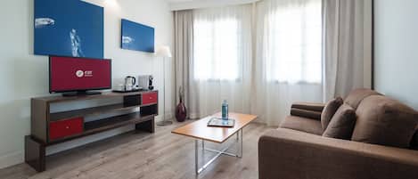 Un soggiorno moderno con un divano, un tavolino, una TV e opere d'arte alle pareti.