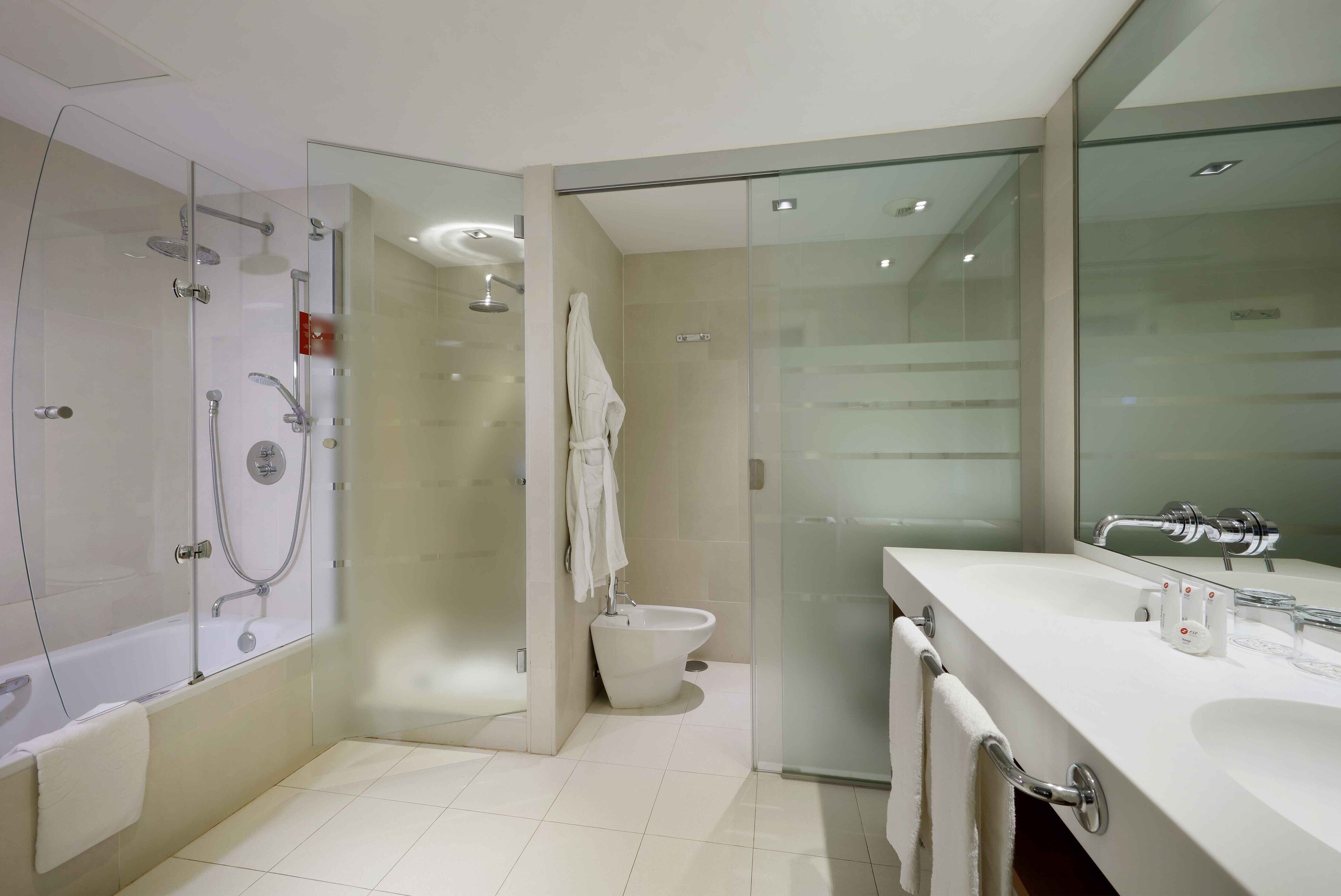 Ein modernes Badezimmer mit einer begehbaren Glasdusche, einem weißen Waschbecken und einem großen Spiegel.